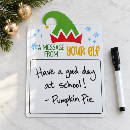 Acrylic elf Christmas dry-erase message board on a white tabletop with an example handwritten note and marker.