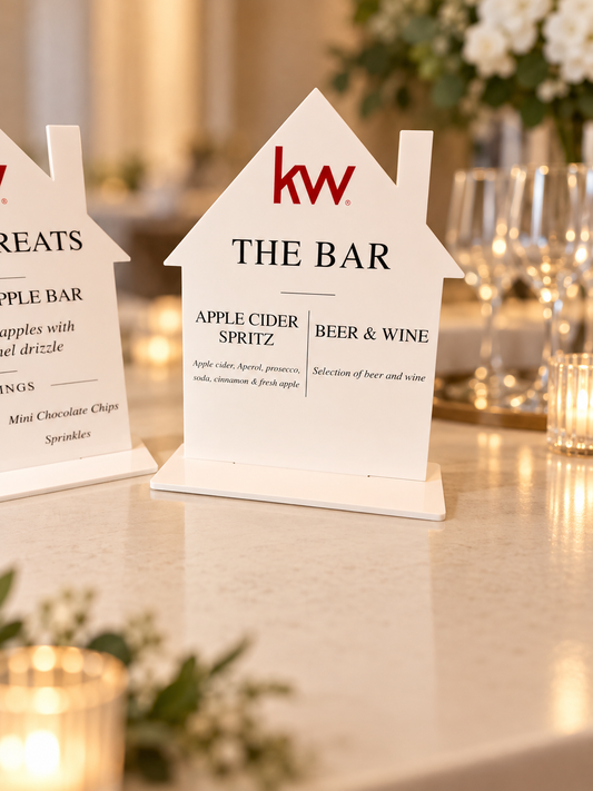 White house-shaped acrylic bar menu sign with a red real estate logo and coordinating white tabletop base.