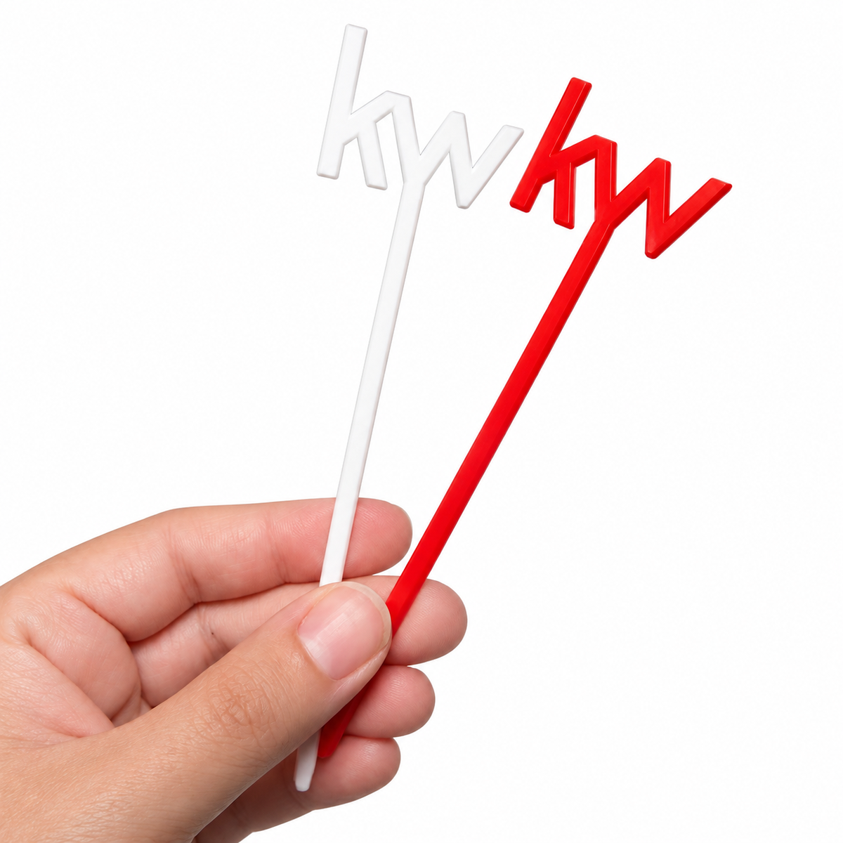 A hand holding two small decorative picks on sticks, one white and one red, both with stylized lettering on a plain white background.