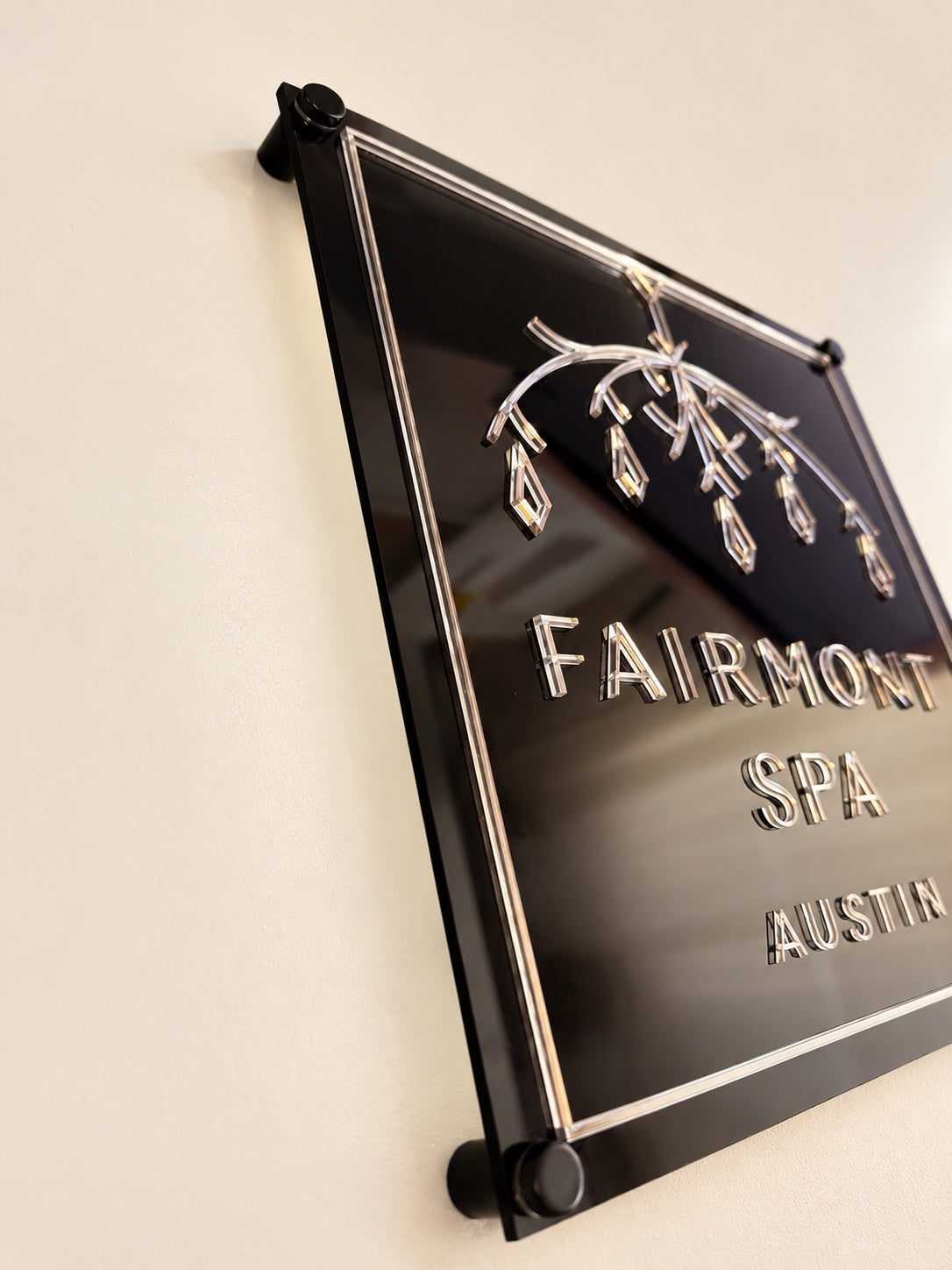 Angled detail of reflective lettering and a mirror border on a black layered acrylic business logo sign.