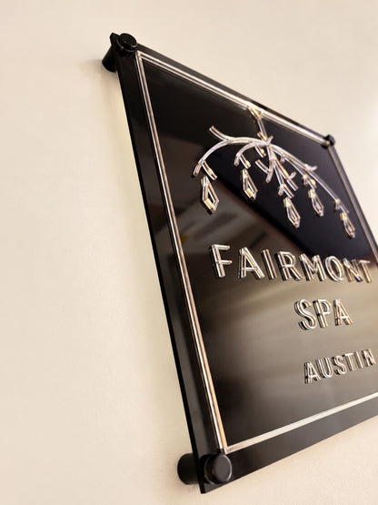Angled detail of reflective lettering and a mirror border on a black layered acrylic business logo sign.