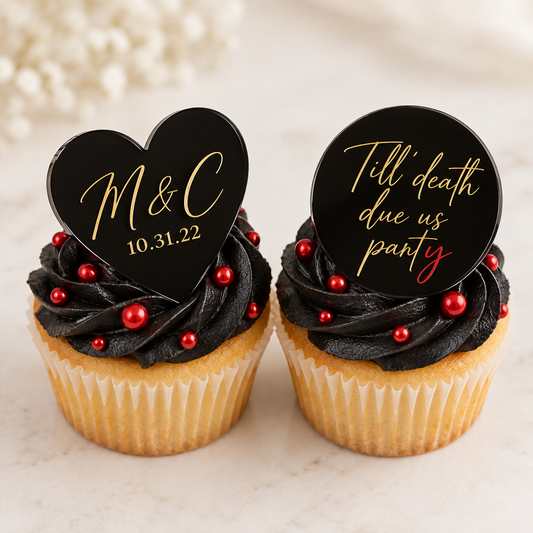 Black heart and circle acrylic cupcake charms with personalized gold lettering on black-frosted cupcakes decorated with red candy pearls.