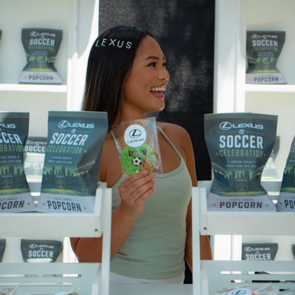Custom snack bags displayed beside a woman looking to the side holding a packaged cookie