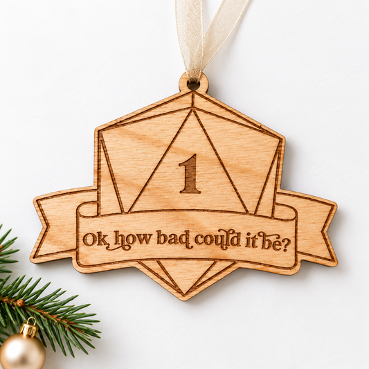 Plywood D20 dice Christmas ornament with engraved natural 1, funny banner and sheer beige ribbon.