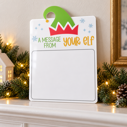 Blank acrylic elf Christmas dry-erase message board leaning on a mantel with festive greenery.