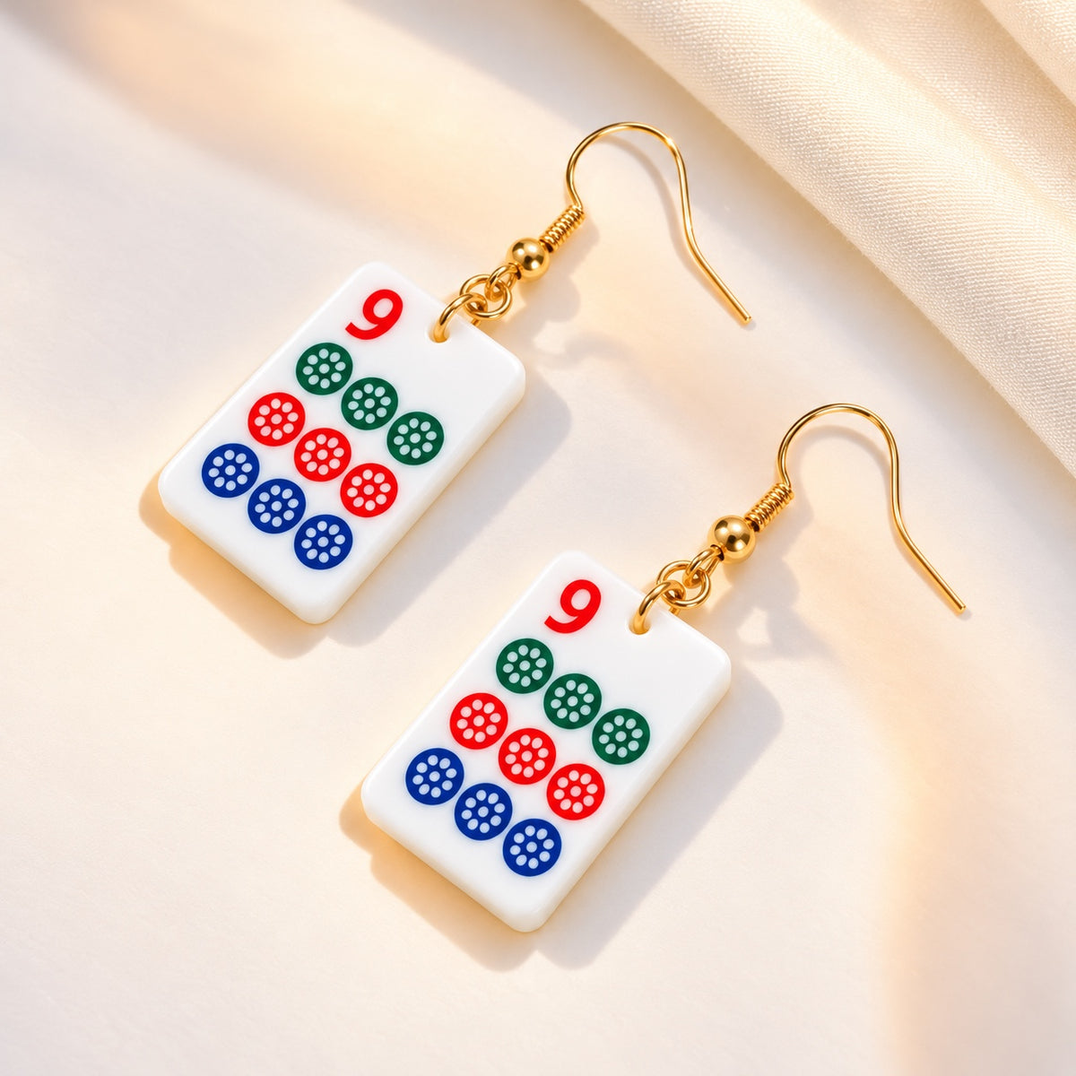 White acrylic nine-dot mahjong tile earrings with green, red and blue circles and gold-tone fishhook ear wires.