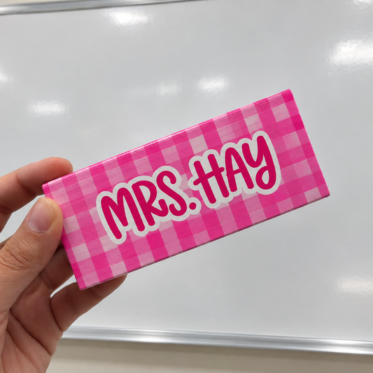 Personalized pink checkered dry erase eraser held in front of a whiteboard