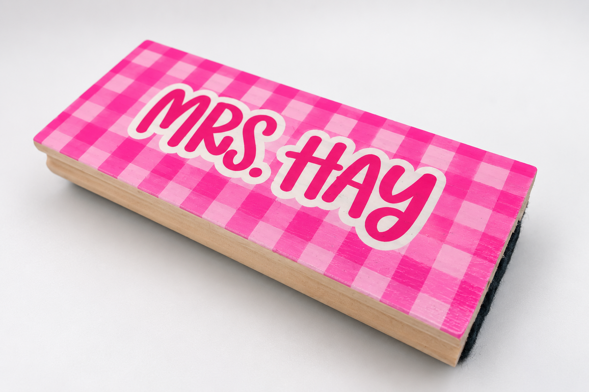 Angled view of a pink checkered whiteboard eraser customized with a teacher name