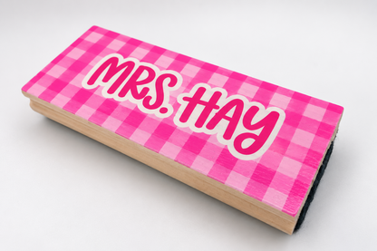 Angled view of a pink checkered whiteboard eraser customized with a teacher name