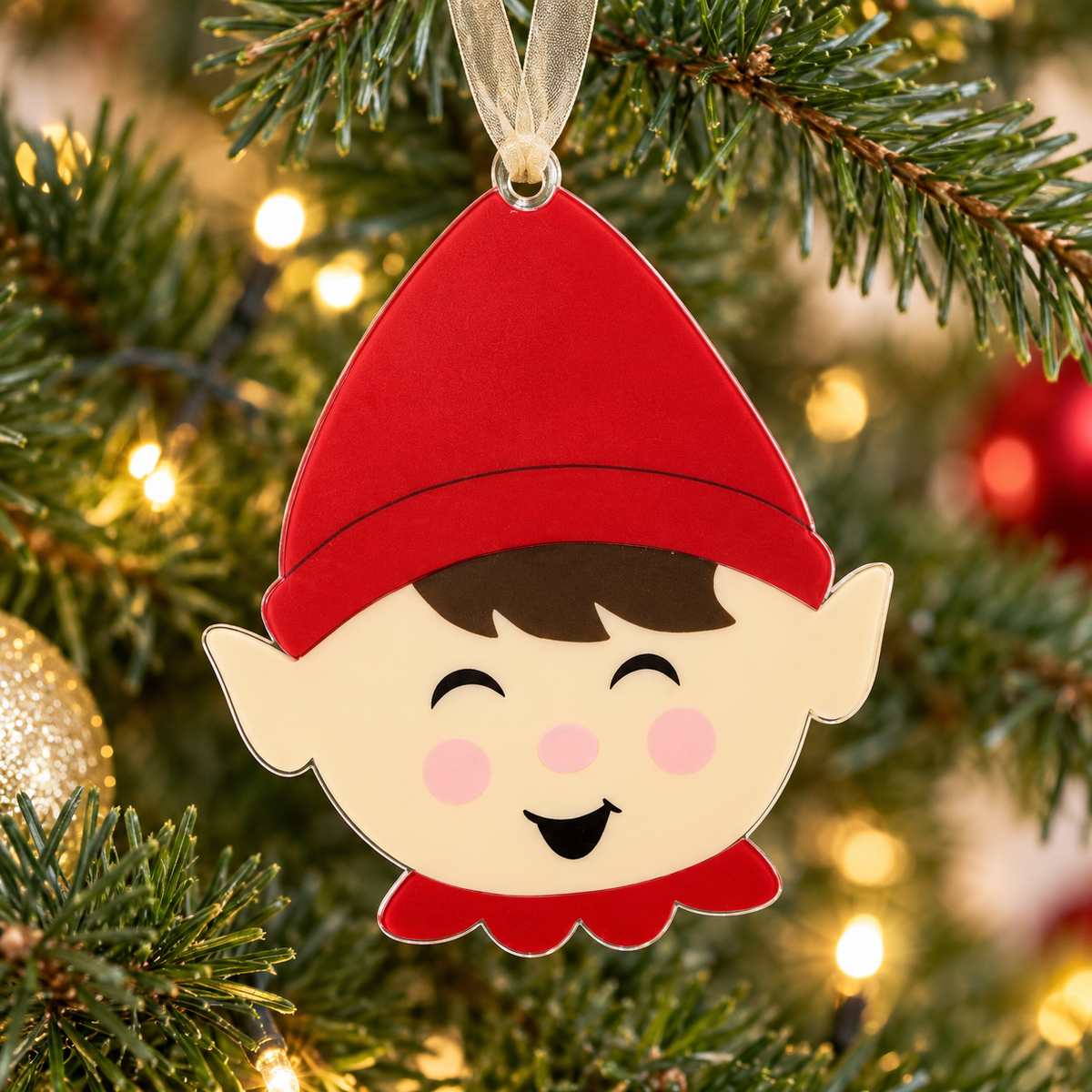 boy elf UV printed acrylic Christmas ornament hanging on a Christmas tree, with sheer beige ribbon.