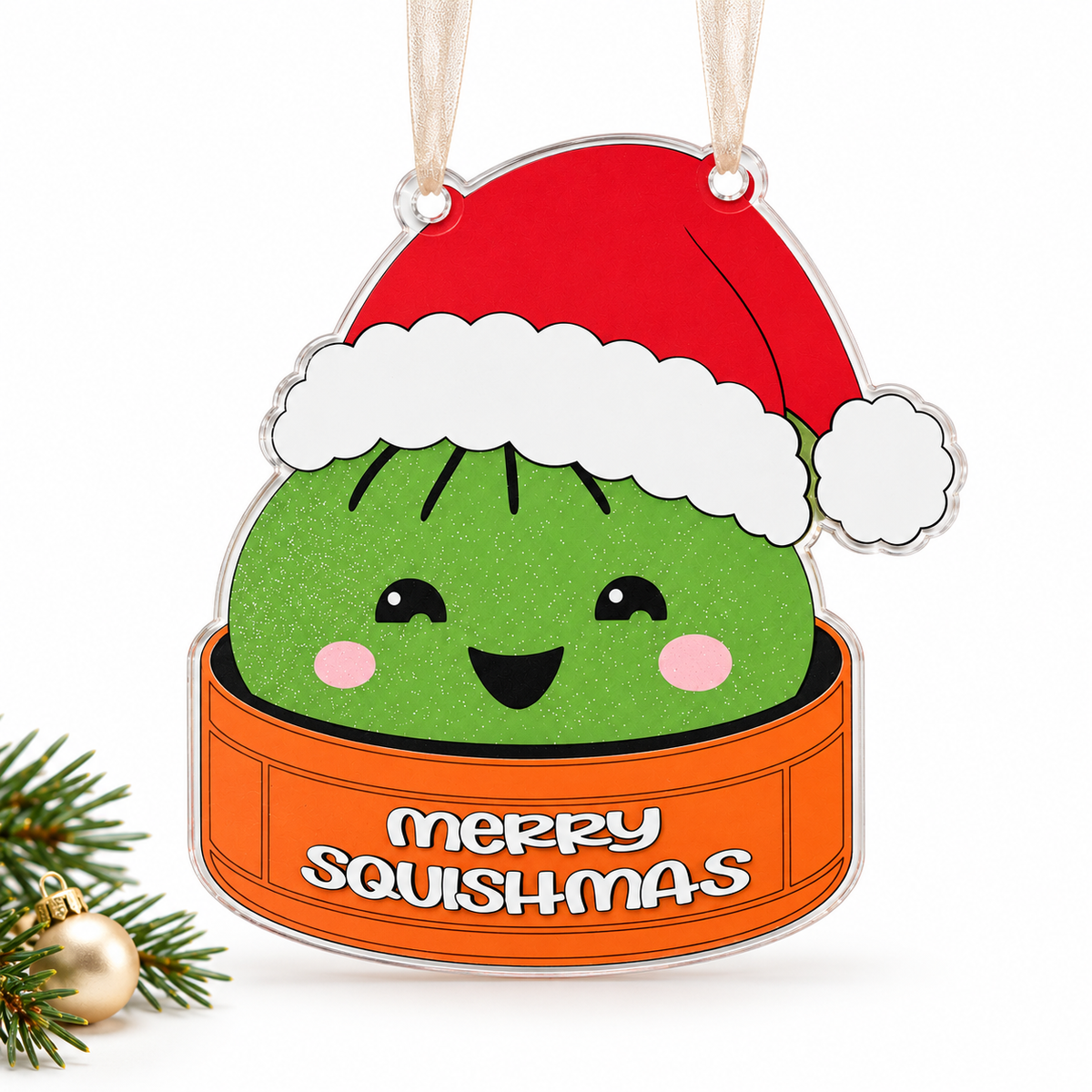 Green merry squishmas UV printed acrylic Christmas ornament on a white background, with sheer beige ribbon.